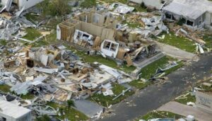 The aftermath of a hurricane, houses completely ripped apart and destroyed, debris all over the place.