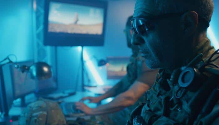 Military commander sitting down in front of a screen at an operations center.