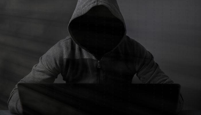 Anonymous man wearing a hoodie, on a computer using a VPN